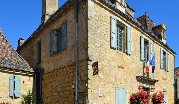 Une mairie de village en pierre, drapeaux en façade